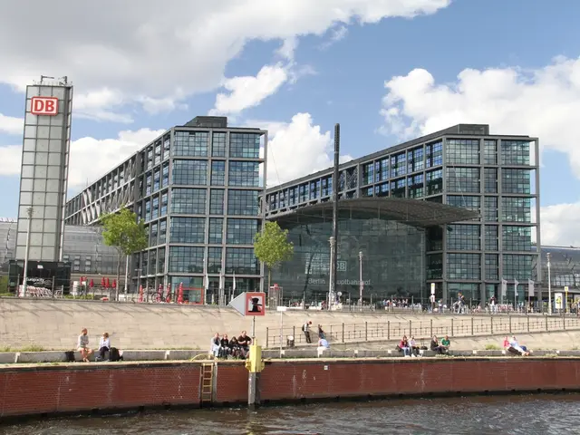 Sky is cloudy. Buildings with glass windows. Front we can see water, fence and people. This is sign...