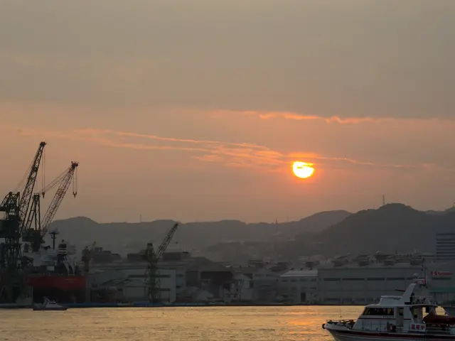 In this image there are few ships in the water, few cranes, towers, few buildings, mountains, the...