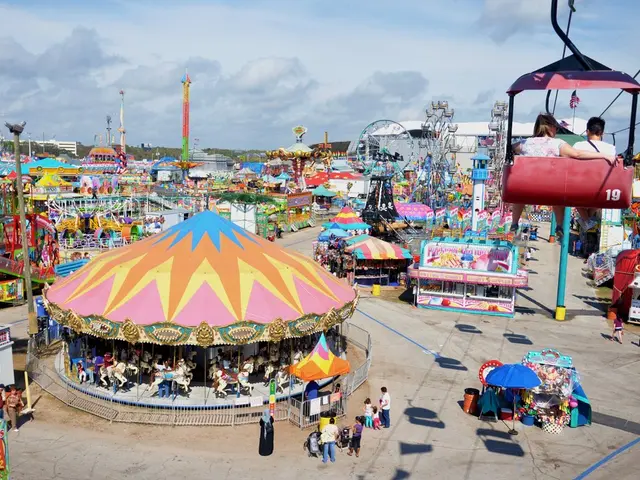 It is a picture of a exhibition. In this picture we can see rides, poles, stalls, boards, people,...